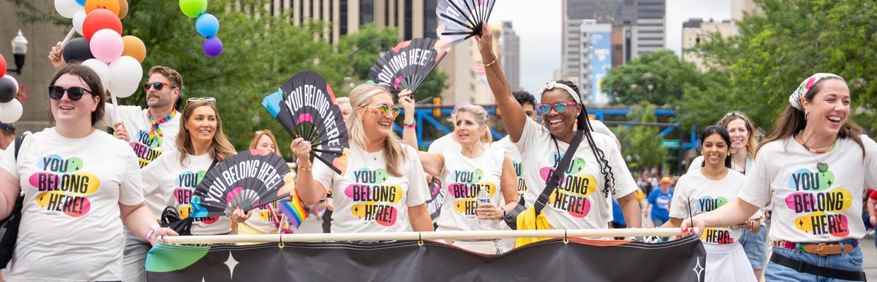 Experience Columbus staff walking in Pride parade with "You Belong Here" merch