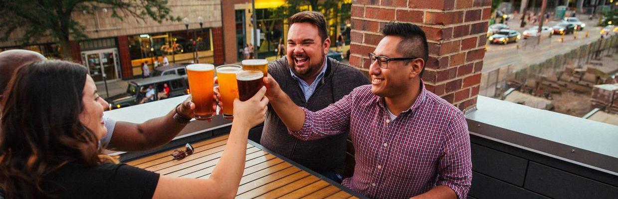 Group of friends clinking beers on rooftop patio in the Short North