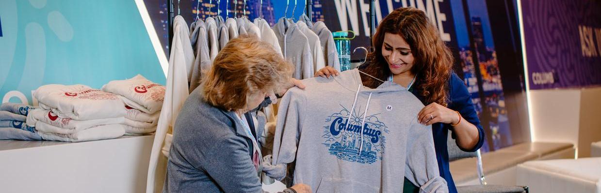 Two women looking at Columbus branded hoodie